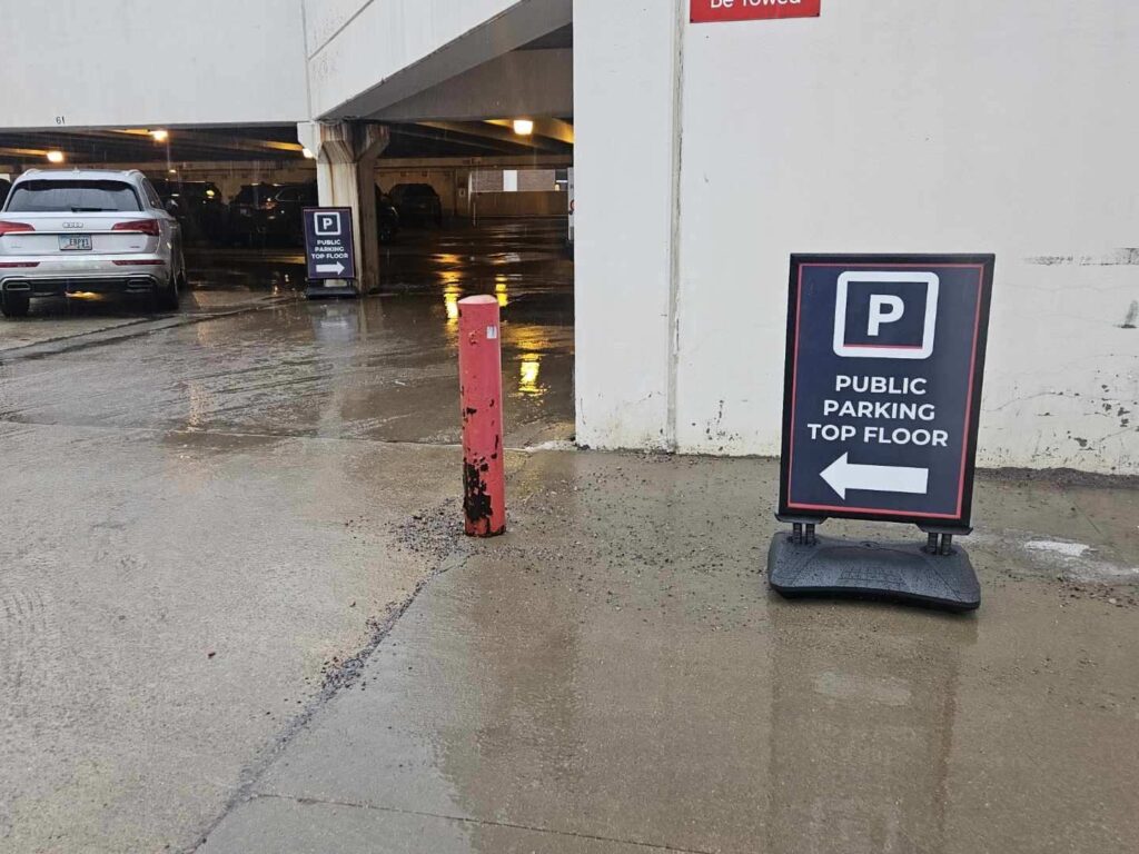 Two PMC signs leading into a multi-level parking garage entrance point to public parking on the top floor.