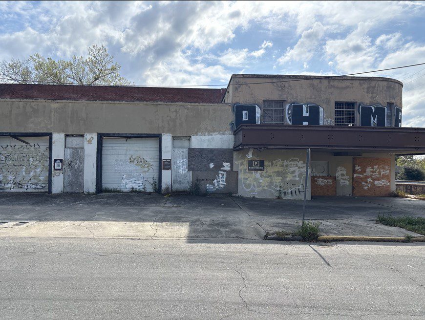 An empty Parking Management Company parking garage with three separate parking signs posted on a building in the background. One on the left has a QR code for digital payments.