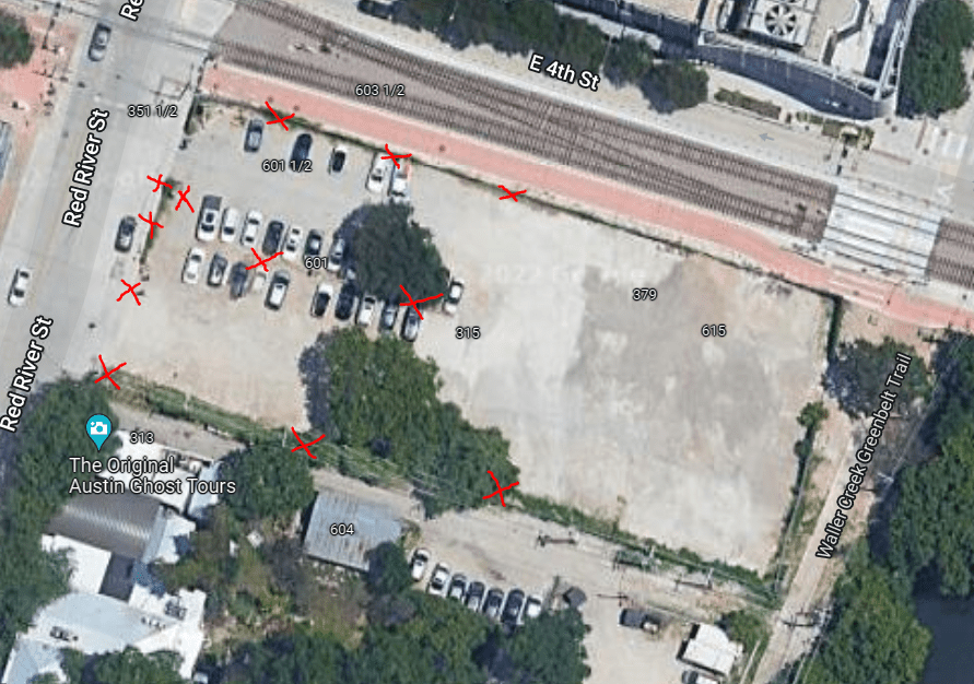 Aerial view of a parking lot at Red River St and E 4th St in Austin. Several cars are parked on the left, and red Xs mark certain parking spots and areas. Nearby buildings and trees are visible.